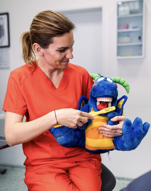 36 dentální hygienistka demonstruje čištění zubů na plyšákovi